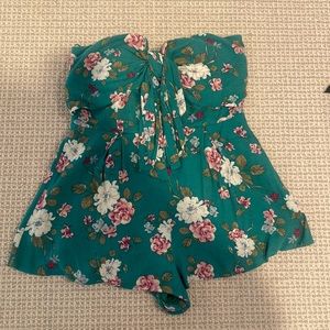 Green romper with white and pink floral detailing and bow in the front.